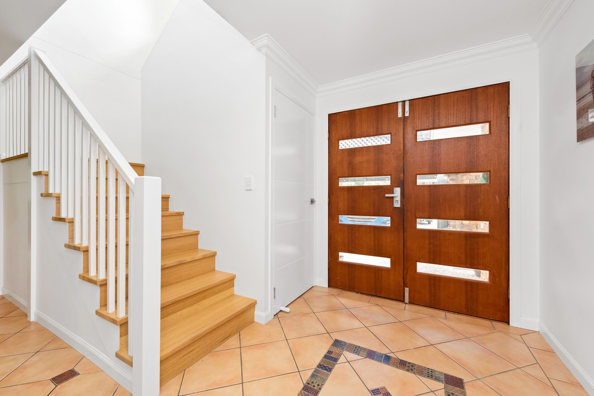 New Victorian Ash hardwood internal stairs with Painted white square vertical balustrades adjoining hardwood front entry doors