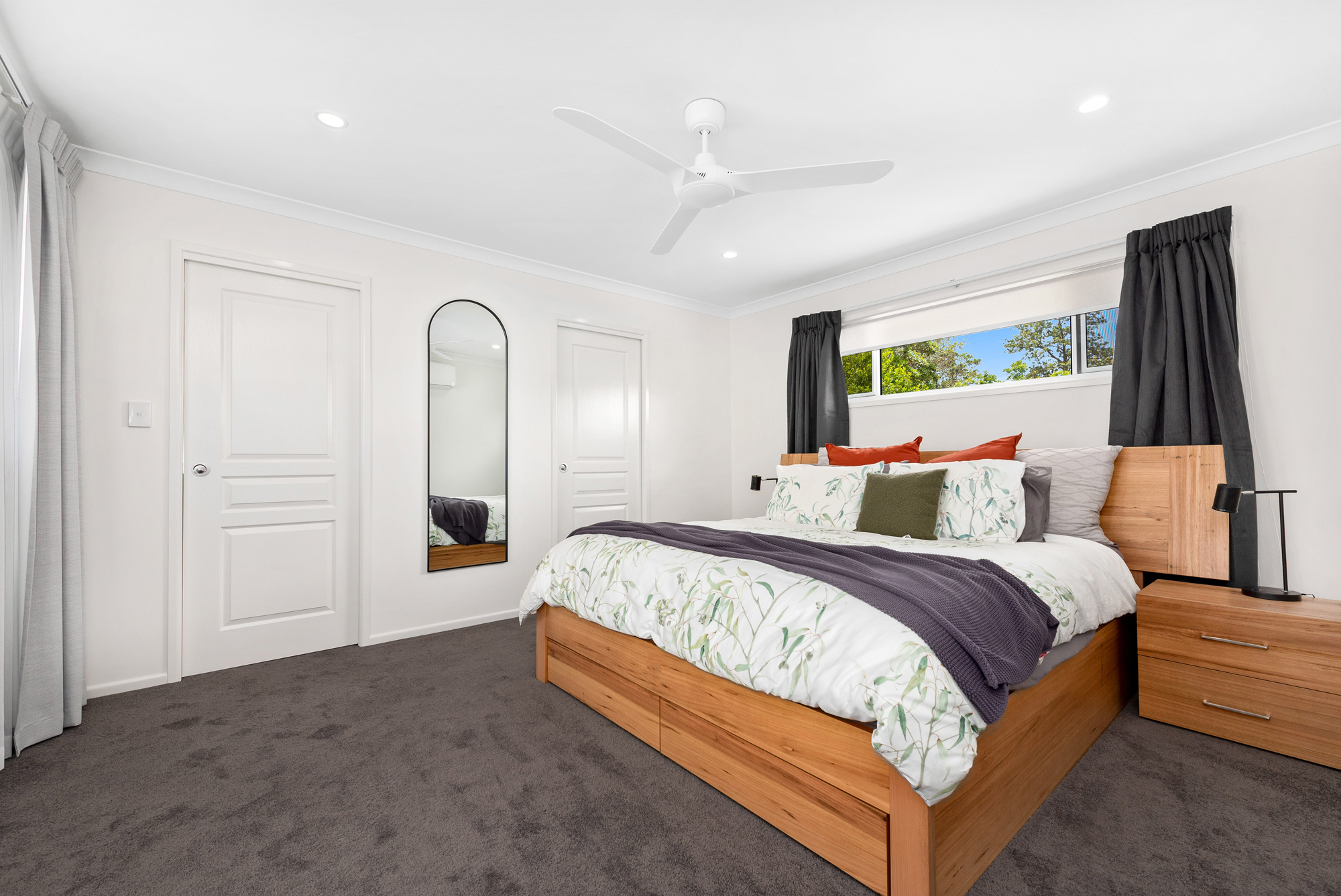 Second storey master bedroom with grey carpet and wooden king bed